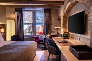 a hotel room with a bed and a desk with a television at Hôtel Les Armures in Geneva