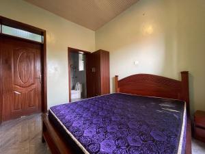 um quarto com uma cama roxa e uma porta de madeira em MyPlace Suites 2-Bed Apartment Kagarama Kigali em Kigali