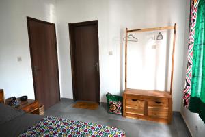 a bedroom with a bed and a dresser and a mirror at Les Amazones Rouges Chambre Verte in Ouidah