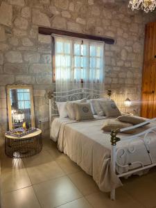 a bedroom with a white bed and a stone wall at Florence Dreaming House in Pissouri