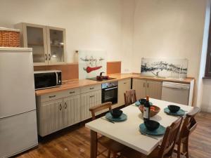 a kitchen with a table with chairs and a white refrigerator at Kaya Rentals in Belvès