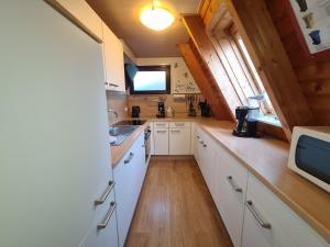 małą kuchnię z białymi szafkami i zlewem w obiekcie Haus Blume w mieście Carolinensiel