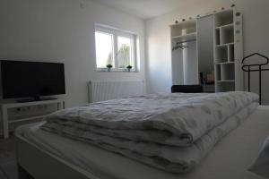 a white bedroom with a bed and a flat screen tv at Ruhige Ferienwohnung in der Kernstadt Laubach in Laubach
