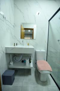 uma casa de banho com um lavatório, um WC e um espelho. em Apart Hotel Neri em Sinop