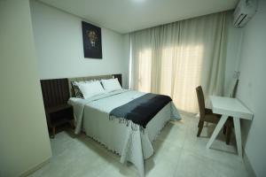 um quarto com uma cama, uma secretária e uma janela em Apart Hotel Neri em Sinop