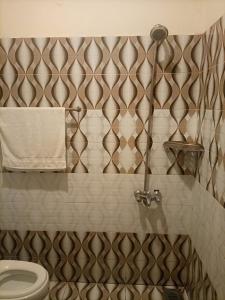 a bathroom with a toilet and a tiled wall at Go Guest House Lahore in Lahore