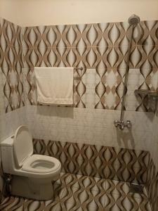 a bathroom with a toilet and a tile wall at Go Guest House Lahore in Lahore