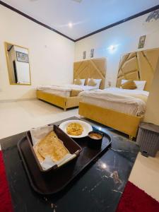 een hotelkamer met 2 bedden en een dienblad met eten bij Go Guest House Lahore in Lahore