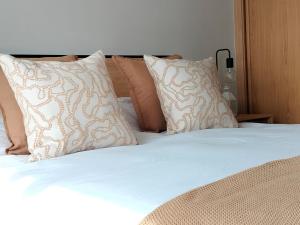 una cama con sábanas blancas y almohadas en HM Combarro, en Combarro 9 fotos más