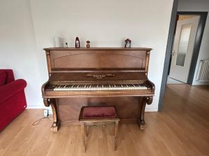 a brown piano sitting in a living room at "Spacious Family Apartment & Parking near Strasbourg Center with easy bus Access" in Bischheim