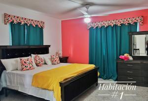um quarto com uma cama com cortinas verdes e vermelhas em Camu em Camú