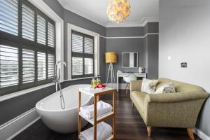 a bathroom with a tub and a chair and a couch at Ravilious in Eastbourne