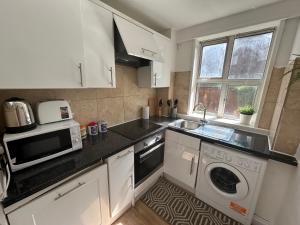 a kitchen with a sink and a microwave and a dishwasher at Marble Arch 3-Bedroom Family Flat in Central London in London