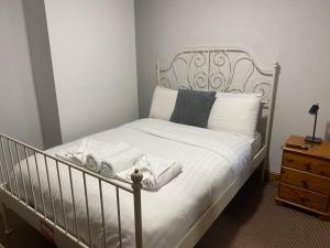 a bed with a metal frame and white sheets and pillows at A secured 3 bedroom family home in Radcliffe
