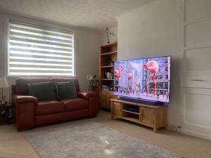 a living room with a couch and a flat screen tv at A secured 3 bedroom family home in Radcliffe