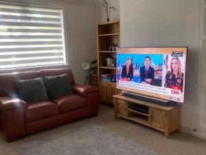 uma sala de estar com um sofá e uma televisão de ecrã plano em A secured 3 bedroom family home em Radcliffe