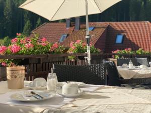 a table with plates and cups and an umbrella at Schwarzwald-Hotel Kraeutle in Feldberg