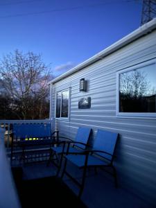 two chairs and a table on a deck next to a trailer at Laguna- Rockley Park Poole in Poole