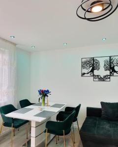 a dining room with a white table and green chairs at Ferienhaus Doina in Gehlberg