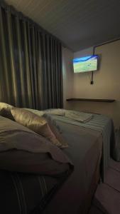 a bedroom with a bed with a television on the wall at Pousada Sol e Mar in Farol de Santa Marta