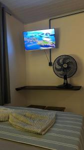 a bedroom with a flat screen tv and a fan at Pousada Sol e Mar in Farol de Santa Marta