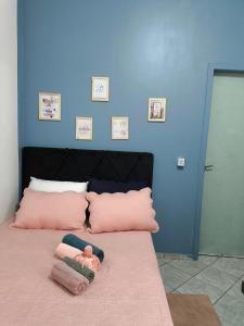 a doll sitting on a bed with pink pillows at Kitnet Aconchegante in Foz do Iguaçu