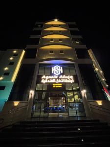 a tall building with a sign on it at night at Horizon Hotel Suites in Hail
