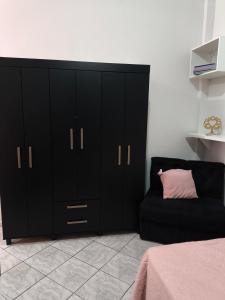 a bedroom with black cabinets and a black couch at Kitnet Aconchegante in Foz do Iguaçu +8 photos