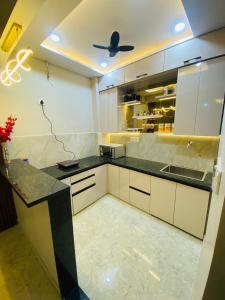 a kitchen with white cabinets and a ceiling fan at DeeHa Niwas Luxe -Modern Luxury 1BHK in City Centre in Varanasi
