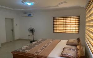 a bedroom with a bed and a window with a fan at Rose Villa in Spintex