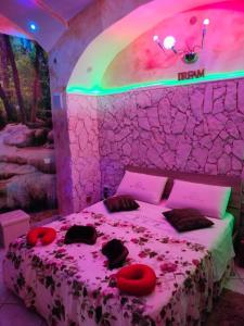 una camera con un letto in una stanza con luci rosa di il Grottino di Giannas a Pozzuoli