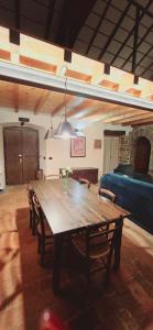 een houten tafel in een kamer met stoelen en een bank bij Historical House Medieval Abbey - Al Chiostro in Sotto il Monte