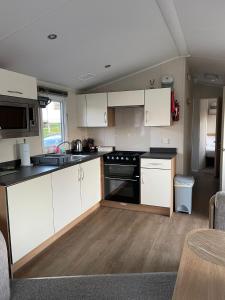 a kitchen with white cabinets and a stove top oven at Luna-Rockley Park Poole in Poole