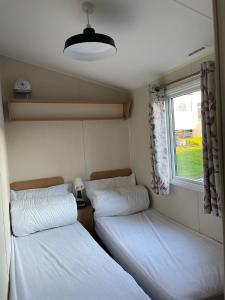 2 letti in una piccola camera con finestra di Luna-Rockley Park Poole a Poole