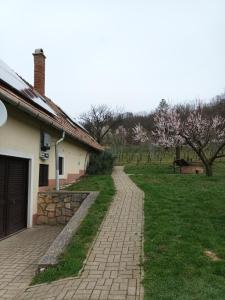 a brick walkway next to a house with a yard at Kéknefelejcs Vendégház in Tapolca