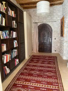 een kamer met een tapijt en een boekenplank bij Dar Volubilis spacieuse villa avec piscine, 5 chambres vue sur forêt in Essaouira