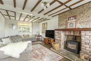a living room with a brick fireplace and a couch at Old Lodge Cottage, dog friendly and rural in Kempley