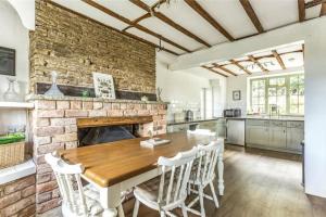 a kitchen with a wooden table and a brick wall at Old Lodge Cottage, dog friendly and rural in Kempley