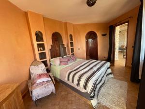 een slaapkamer met een bed en een stoel erin bij Dar Volubilis spacieuse villa avec piscine, 5 chambres vue sur forêt in Essaouira