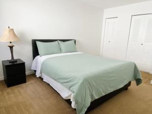 a white bedroom with a bed and a lamp at Lovely 3 bedrooms 2 bathrooms fourplex near Calgary Downtown in Calgary