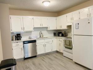 a white kitchen with white cabinets and a refrigerator at Lovely 3 bedrooms 2 bathrooms fourplex near Calgary Downtown in Calgary