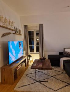 a living room with a couch and a television at Chez Valérian, gare de Chantilly in Chantilly