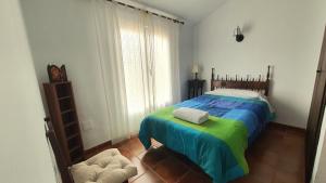 - une chambre dotée d'un lit avec une couverture bleue et verte dans l'établissement Las Candelas, à Casas de los Pinos