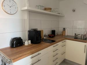 a kitchen with a microwave and a clock on the wall at Ferienwohnung DECK 3 in Cuxhaven in Cuxhaven