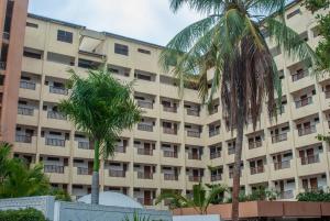 a large building with palm trees in front of it at Harmony Homes Beachfront in Diani Beach