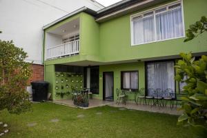 una casa verde con sillas y mesas en un patio en Hotel Regine's Manizales en Manizales