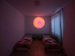 two beds in a room with a large orange orb on the wall at Private room in Art Centre 