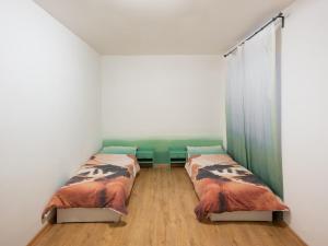 two beds in a room with white walls and wooden floors at Private room in Art Centre 