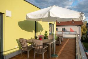 een tafel en stoelen met een parasol op een balkon bij Solid Gold - OPENING AUGUST 2024 in Malacky