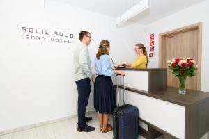 Solid Gold - OPENING AUGUST 2024 في مالاتسكي: رجل وامرأة يقفان في مكتب الاستقبال
